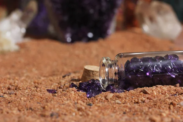 Jar of Purple Stones on Australian Red Sand With Crystals in Background. Meditation Altar
