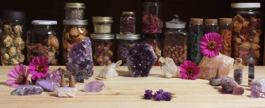 Amethyst Crystals and Flowers On Meditation Table With Jars of Dried Herbs in Background