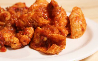 Fried Pork Skins With Red Salsa on Wooden Table in Rustic Kitchen