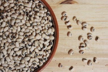 Tahta masadaki kasede pişmemiş siyah göz bezelyeleri.