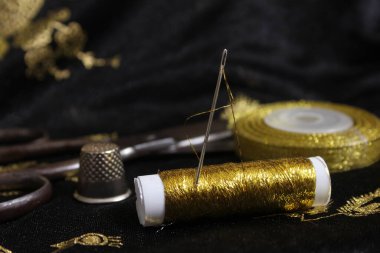 Spool of Gold Thread With Thimble on Metallic Chiffon Fabric