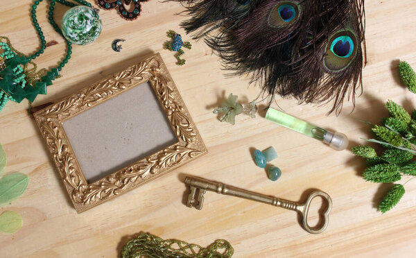 Green Jewelry and Peacock Feathers With Gold Picture Frame on Wood Back
