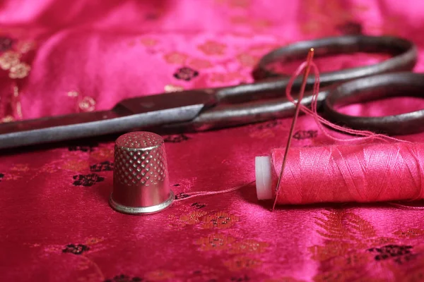 Spool of Pink Thread and Thimble on Vintage Pink Satin