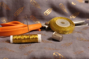 Spool of Metallic Gold Thread on Gray and Gold Fabric