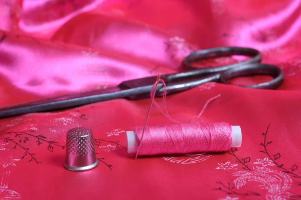 Spool of Pink Thread and Thimble on Vintage Pink Satin