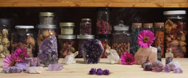 Amethyst Crystals and Flowers On Meditation Table With Jars of Dried Herbs in Background