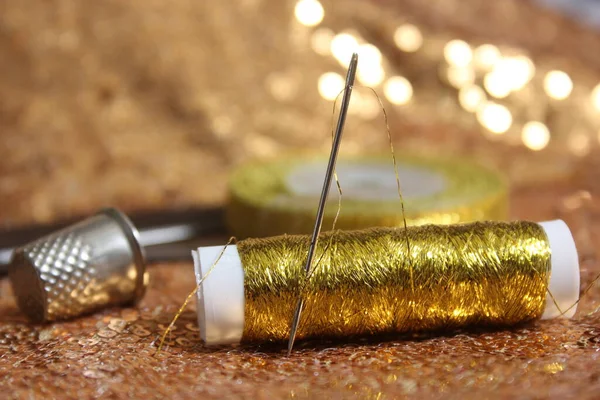 Gold Sequins on Fabric With Spool of Gold Thread and Thimble