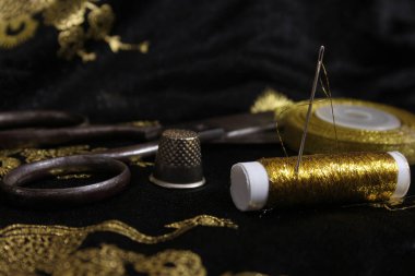 Spool of Gold Thread With Thimble on Metallic Chiffon Fabric