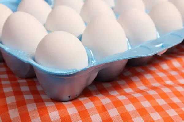 Carton of Eggs on Rustic Table With Orange Checkered Table Cloth