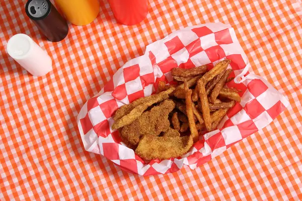 Fried Catfish Basket With French Fries in Rustic Cafe on Checkered Background