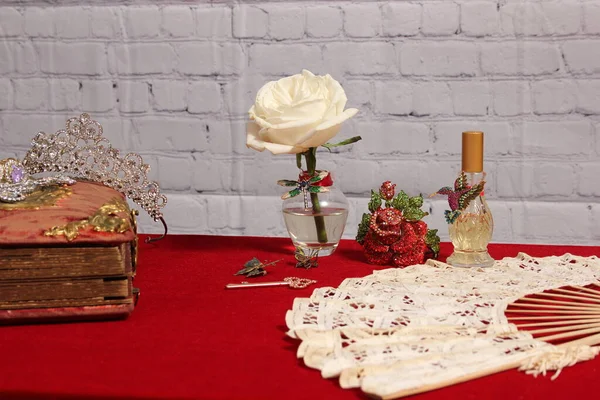 White Rose in Vase Next to Vintage Rhinestone Rose and Perfume Bottle on Red Velvet Table