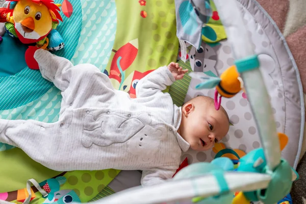 新生婴儿躺在操场上 婴儿体育馆用数字 玩具和色彩刺激她 幼儿早期刺激的概念 — 图库照片