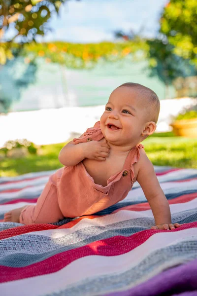 小宝宝笑着坐在花园里一张彩色的毛毯上玩耍 — 图库照片