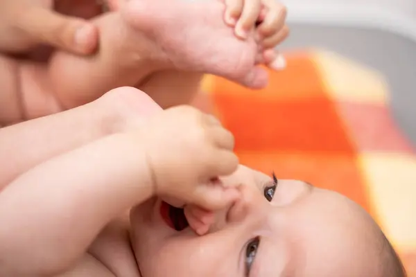 Маленькая Улыбающаяся Малышка Лежит Одеяле Засунув Ноги Рот Дискомфорта Вызванного Лицензионные Стоковые Фото