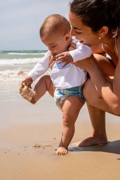 Вертикальная Фотография Молодой Матери Ребенка Пляже Впервые Ребенок Касается Песка Стоковое Изображение
