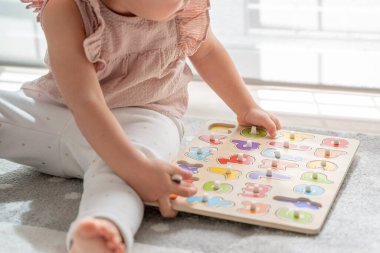 Tahta alfabe harfi yapbozuyla oynayan küçük bir kızın resmini kapat. Montessori metodolojisi ve materyalleri, eğitim, gelişme ve çocukluk döneminde öğrenme