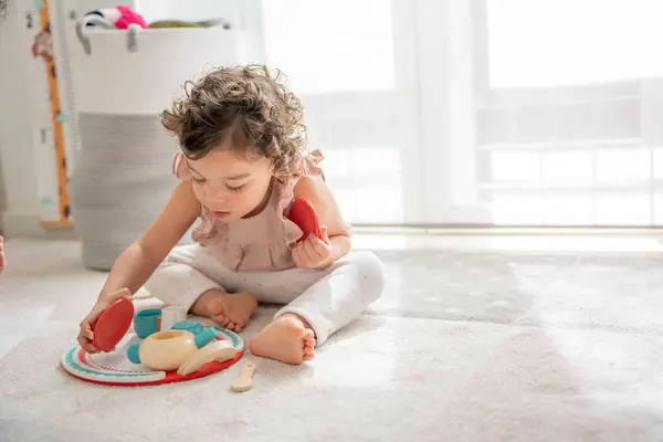 Маленькая Двухлетняя Девочка Играет Сидя Полу Своей Комнаты Деревянной Игрушкой Стоковое Изображение