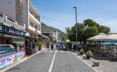 Sutomore, Karadağ-6 Eylül 2024 Turistik Bölgenin ana caddesinde insanlar yürüyor. Arka planda mavi gökyüzü.