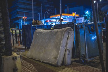  Şehirdeki bir çöp konteynırının yanındaki şiltenin fotoğrafı. Gece fotoğrafı, şehir hayatı konsepti..