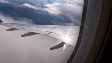 Uçağın içindeki görüntüler uçuşta uçağın kanadını gösteriyor. Arkaplanda büyük bulutlar ve güzel manzaralar..