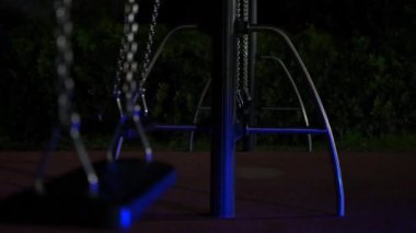 Statik çekim görüntüleri, bir polis arabasının ışıkları yanıp sönerken, halk parkında sallanan boş bir salıncağı gösteriyor..