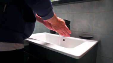 Statik çekim görüntülerinde sıvı sabun yalayan ve ellerini yıkadığı bir ev var..
