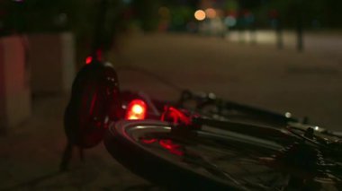 Arka tekeri dönen ve bir ambulansın yanıp sönen ışıklarıyla asfalttaki bir bisikletin görüntülerini kapatın. Gece görüntüleri, kaza konsepti.