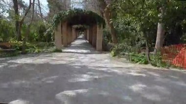 Atina, Yunanistan-23 Mart 2022. Güneşli bir günde Ulusal Bahçe Parkı 'ndaki bir kemerin altında videoyla zaman sarmalı yürüyüş.