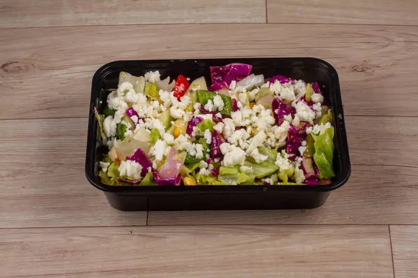 Ahşap zemin üzerinde siyah kapta Yunan Salatası