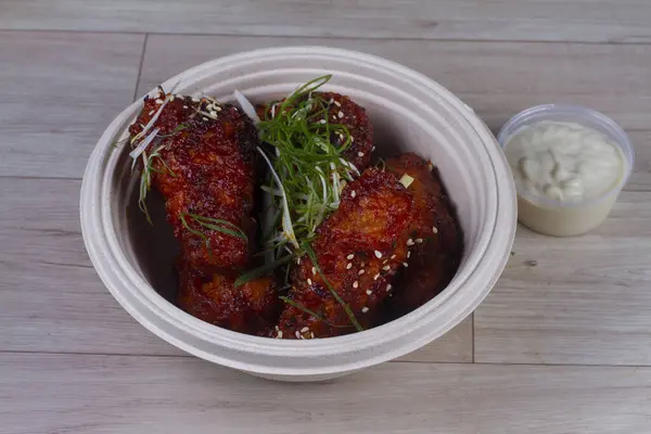 Sticky honey-soy chicken wings in bowl over wooden background.