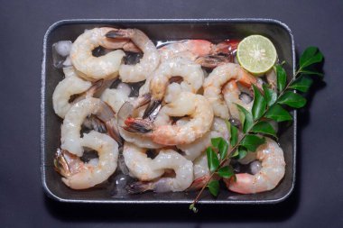 Taze karidesler, limonlu deniz ürünleri, baharatlı limon, ahşap tahtada soyulmuş karides, arka plandaki yemek masası, üst manzara. Boşluğu kopyala.