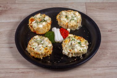 Tahta arka planda yeşil otlu peynirli sarımsaklı ekmek.