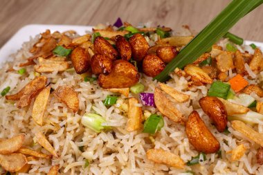 Beyaz seramik tabakta yanmış sarımsaklı sebzeli pilav yakın..