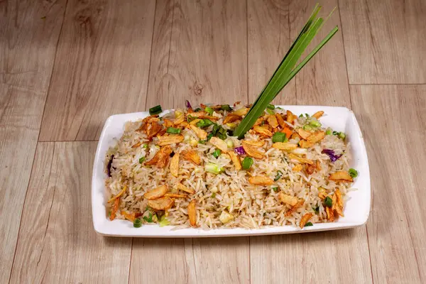 Beyaz seramik tabakta yanmış sarımsaklı sebzeli pilav yakın..