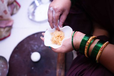 Woman making sweet rice modak stuffed with grated coconut and jaggery clipart