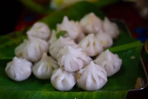 stock image Maharashtrian sweet of Modak that is offered to Lord Ganesh, garnished with kesar (saffron) to be had with Ghee bowl and Lord Ganpati in the background.