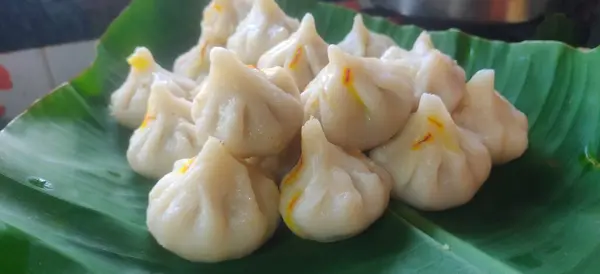 Modak 'ın Maharashtrian tatlısı, arka planda Ghee kasesi ve Lord Ganpati ile süslenmek üzere Tanrı Ganesh' e sunuluyor..