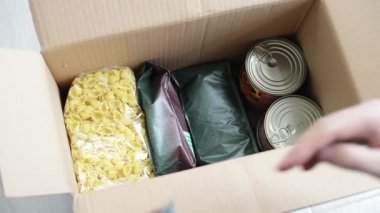 Bir adam savaş ya da salgın sırasında fakirlere bağışlamak için bir kutu yiyecek toplar. Bir kutuda çeşitli ürünler: tahıllar, kolza yağı, ayçiçeği yağı, konserve yiyecek. Yiyecek kutularının toplanması ve teslimatı.