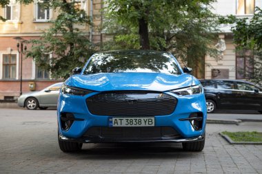 Ivano-Frankivsk, Ukrayna - 12 Haziran 2024: mavi Ford Mustang Mach-E Ford tarafından üretilen bir pil elektrikli kompakt SUV. Şehir caddesinde araba parkı.