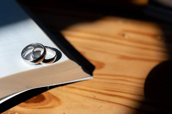 Two wedding rings are placed on the open Bible placed on the table as wedding rings prepared for lovers to wear and read Bible passages as a promise to each other. Copy Space for text