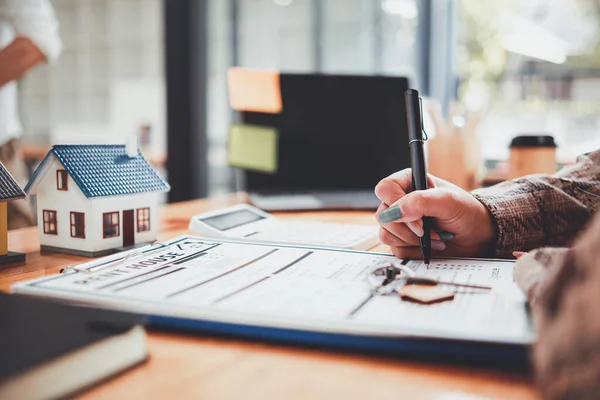 Real estate sales documents and model homes are placed on tables inside real estate sales offices to prepare prospective buyers to sign real estate sales contracts with dealers.