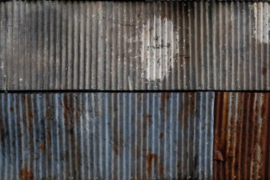 background pattern of rust that eats on the corrugated galvanized sheet used to make the house fence is caused by the weather outside reacting with the galvanized sheet until it corrodes from rust.