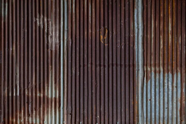 background pattern of rust that eats on the corrugated galvanized sheet used to make the house fence is caused by the weather outside reacting with the galvanized sheet until it corrodes from rust.