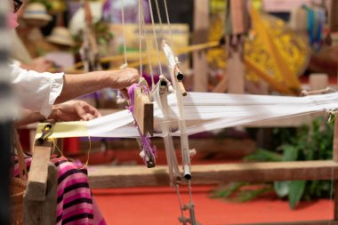 Örgü makinesinin içindeki iplik yerel kumaşları örmek için hazırlanıyor çünkü yerel kumaşlar el yapımıdır ve yüksek bir fiyatı vardır çünkü örmek oldukça uzun zaman alır..