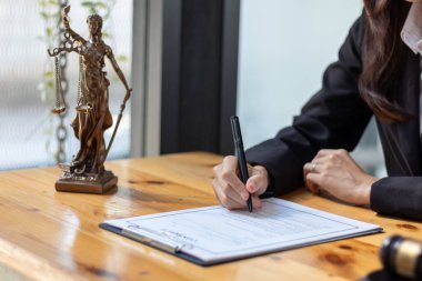 Avukat kontrat belgelerini elinde tutuyor ve işlerini yasalara uygun şekilde yürütmek için hukuki tavsiyeye ihtiyacı olan bir iş adamı ekibi için danışmanlık sözleşmesi imzalamaya hazırlanıyor.