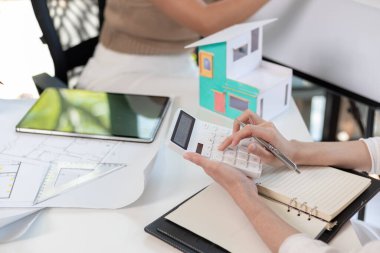 Mühendisler ve tasarımcılar evin planının ve inşaat programının planlandığı gibi tamamlanmasını tartışıyorlar. Profesyonel mühendis ve tasarımcılardan oluşan bir ekiple ev yapımı fikirleri.