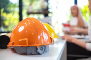 Turuncu başlıklar inşaat mühendislerinin masalarında durur çünkü mühendislerin güvenliği için inşaat sahasına girerken sert şapkalar gereklidir. Başlığı korumak için başlık takma kavramı.