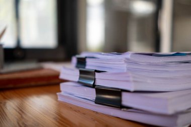İş kadını elleri, iş adamı ile görüşmede doğru belgeleri kullanmaları için yönetim kuruluna göndermeden önce masaya yığılmış belgeleri aramak ve gözden geçirmek üzere kağıt yığınları üzerinde çalışıyor.