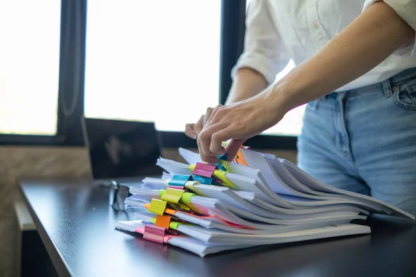 Stock image Businesswoman hands working on stacks of paper documents to search and review documents piled on table before sending them to board of directors to use  correct documents in meeting with Businessman