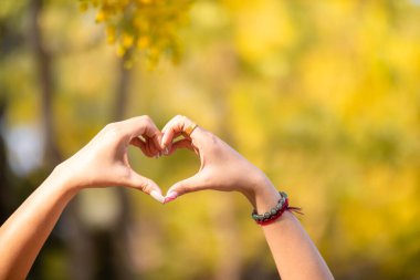 Kadın, sevgi, dostluk ve dostluğu temsil eden bir kalp sembolü oluşturmak için elini başının üstünde tutar. kalp sembolü dostluğu, sevgiyi ve kibarlığı temsil eden bir kavramdır..